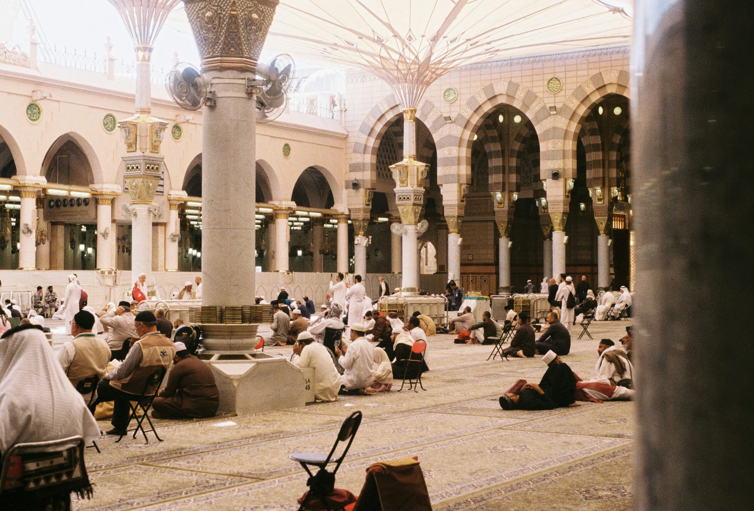 Pilgrims in prayer at Al-Masjid an-Nabawi, showcasing Islamic architecture.