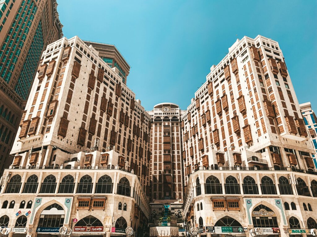 Low angle view of a modern hotel in Makkah under a clear blue sky.