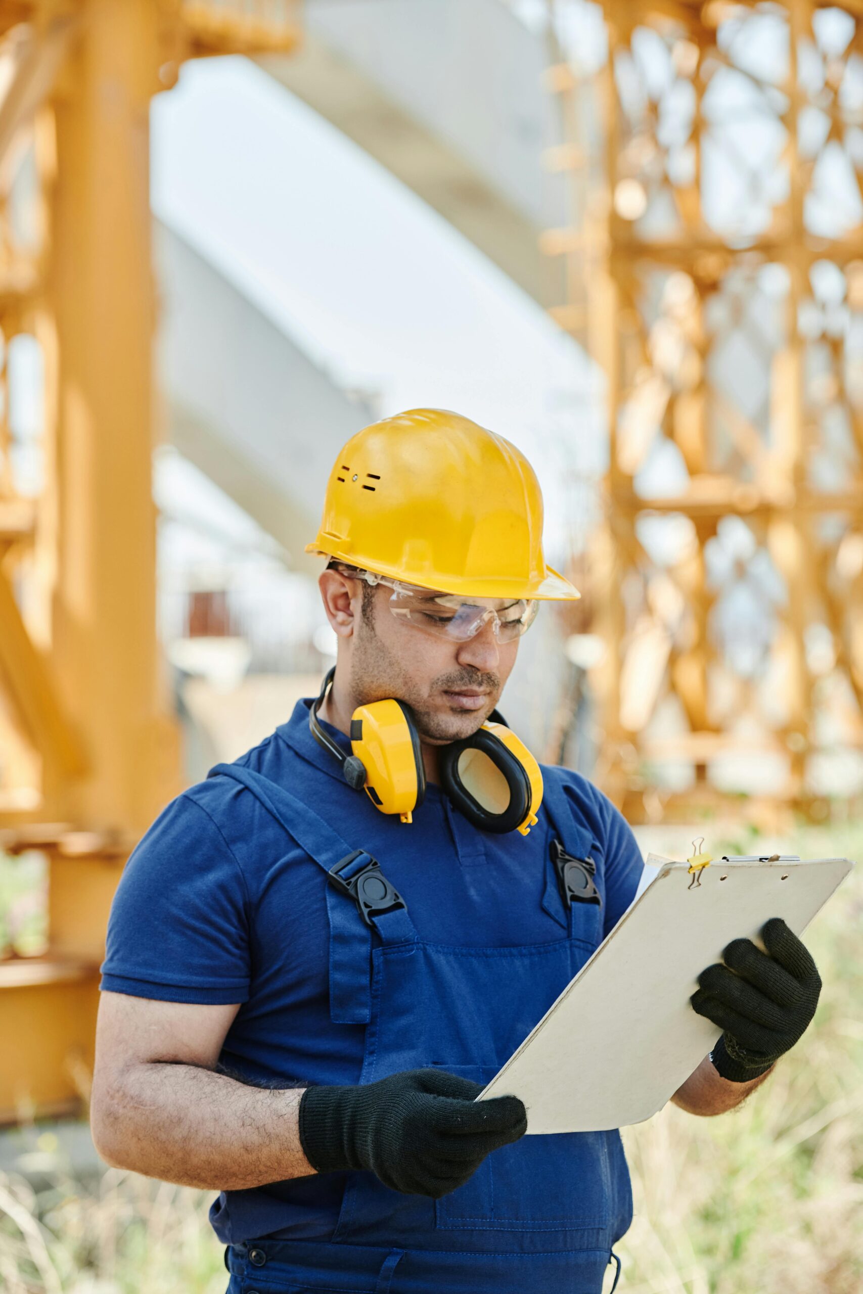 Construction engineer in safety gear reviewing plans at site.